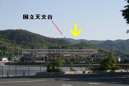 調査地遠景（中央公民館から）。矢印部分が調査現場。手前は県立鴨方高校。の画像