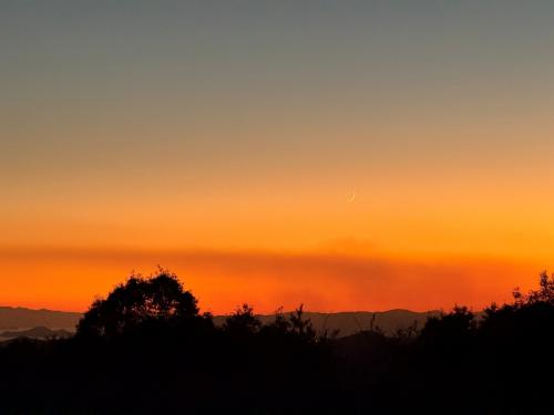 ナナヨンドームがある山の上から西側を撮影した写真。夕暮れのオレンジ色の空に細い月が見える。